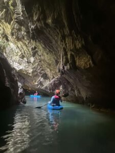 Kayakers paddling through underground limestone cave passages on Belize's 7-Mile Cave Kayak tour along the Caves Branch River, Cayo District